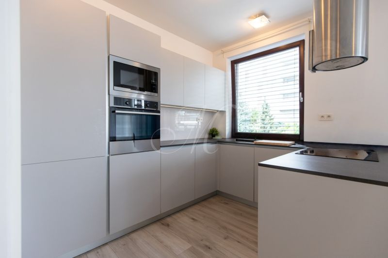 A kitchen in a 2-room apartment with a corner unit and a floor with a wood decor.