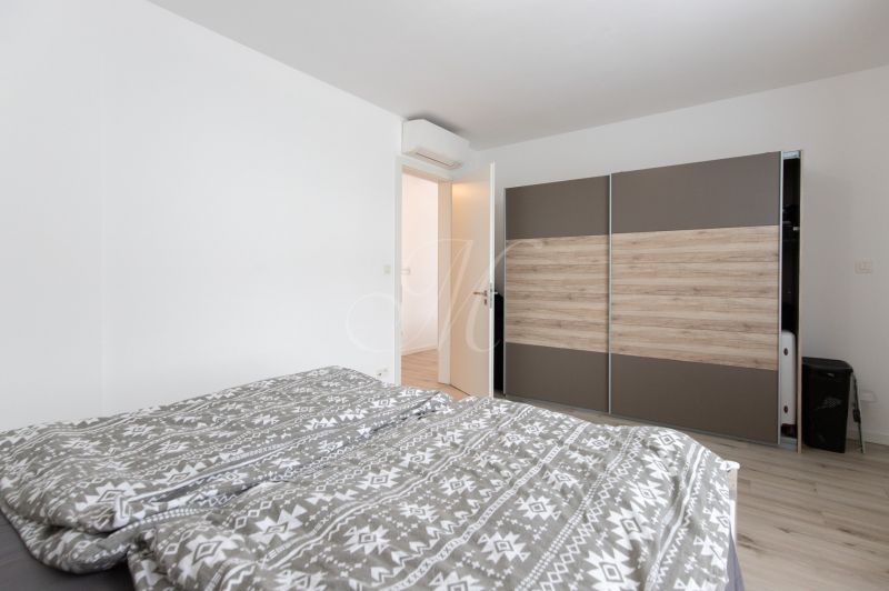 Bedroom in a 2-room apartment with white walls and a wardrobe with a wooden decor.