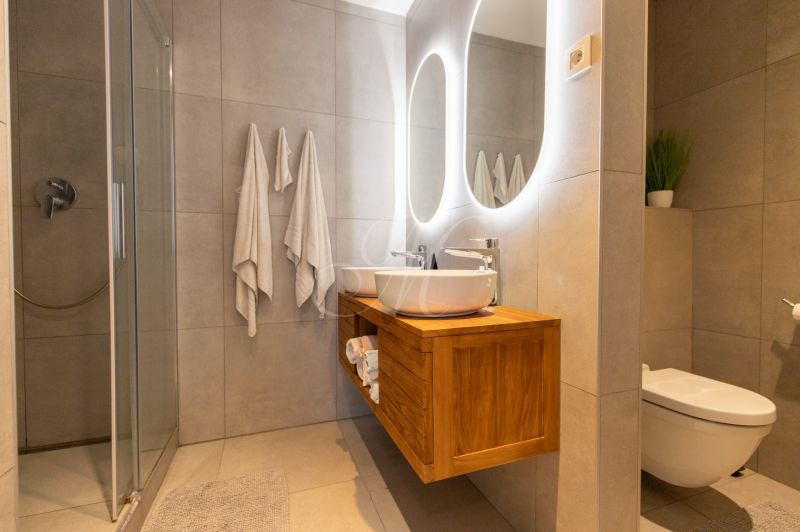 Bathroom in a 2-room apartment with a modern sink, shower, and toilet.