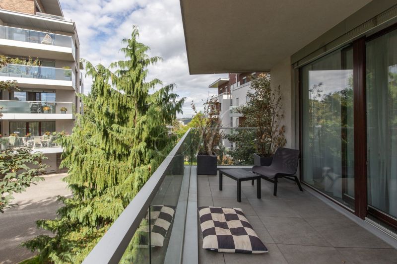 A balcony of a 2-room apartment with a view of greenery and neighboring buildings.