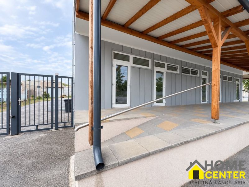 Commercial premises in Komárno with interlocking paving, wooden columns, and a metal gate.