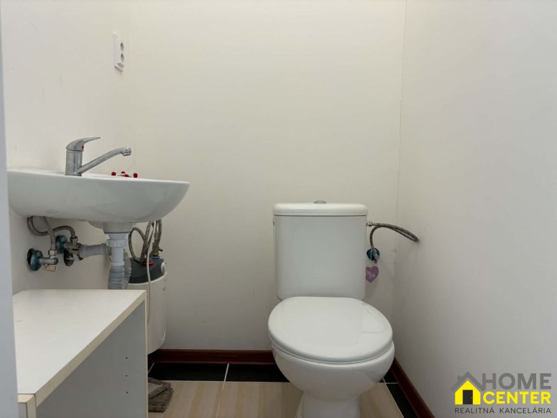 Restroom in commercial premises, with a sink and simple furnishings.