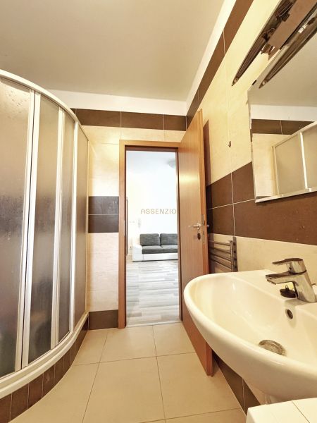 A bathroom in a studio apartment with a spacious shower and a sink.