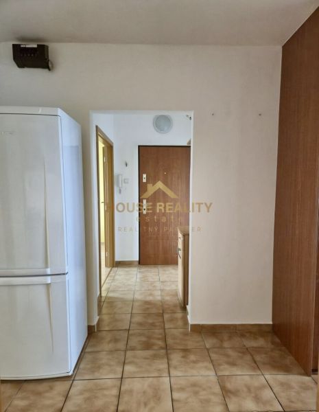 A hallway in a 3-room apartment with a ceramic floor and a white refrigerator.