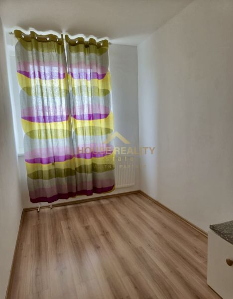 A small room in a 3-room apartment with a wood-patterned floor and colorful curtains.