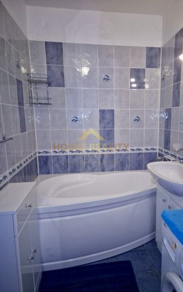A bathroom with a corner bathtub, blue and white tiles in a 3-room apartment.