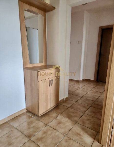 A hallway in a 3-room apartment with a coat rack and a mirror on the tiles.
