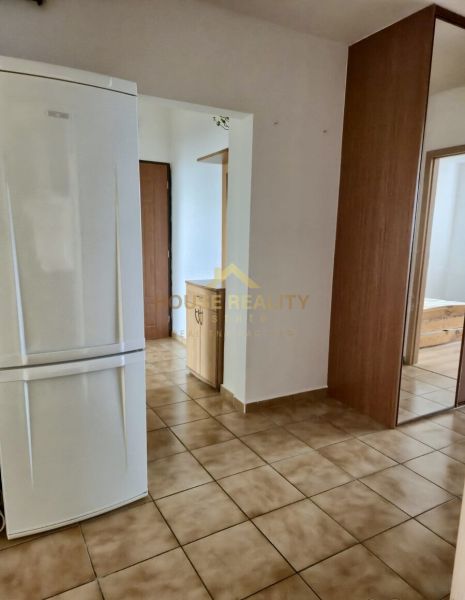 A hallway in a 3-room apartment with tiles and a white refrigerator.