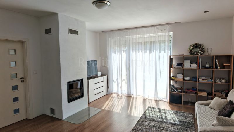 Living room with a fireplace, curtains, and wood-patterned flooring in a family house.