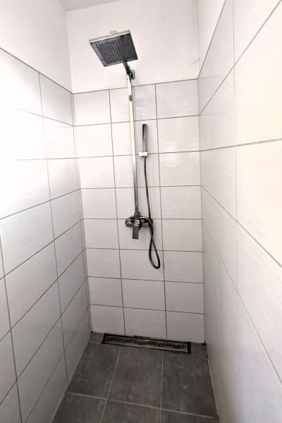 A shower enclosure with a square head and white tiles in a family house.