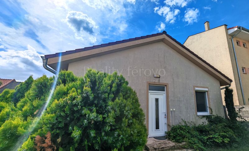 A family house in Matúškovo with white doors, surrounded by greenery under a sunny sky.