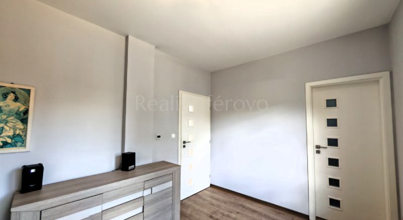 A room with a wooden decor floor, white doors, and a storage cabinet.