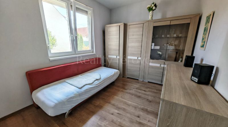 A simple room with a bed, wardrobes, and a wooden decor floor in a family house.