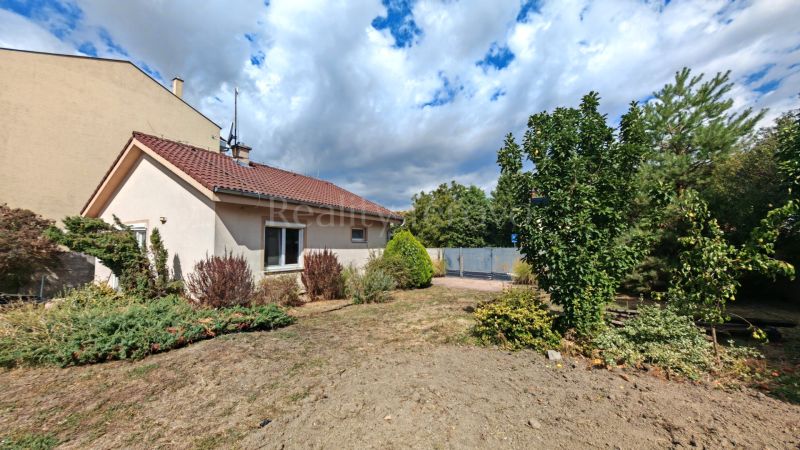 A family house in Matúškovo with a front garden, surrounded by greenery under a cloudy sky.