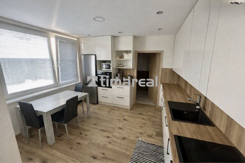 A kitchen in a 3-room apartment with a wooden decor floor and light furniture.