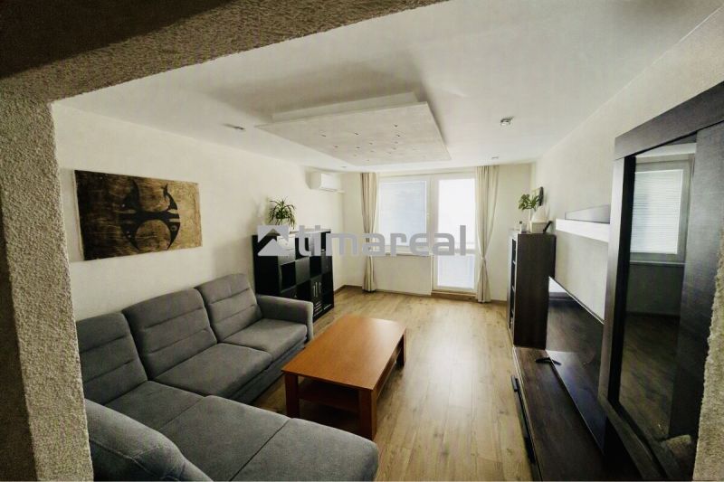 Living room with a large sofa and wooden decor flooring in a 3-room apartment.
