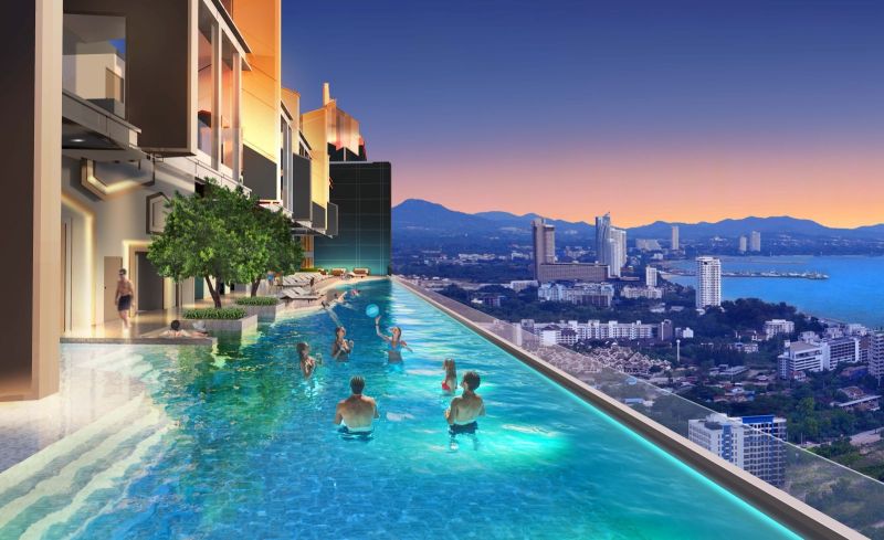 A pool with a panoramic view of Jomtien city from a holiday apartment during sunset.