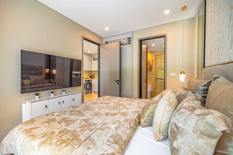 Cozy bedroom with TV and bathroom in a holiday apartment, complemented by plants.
