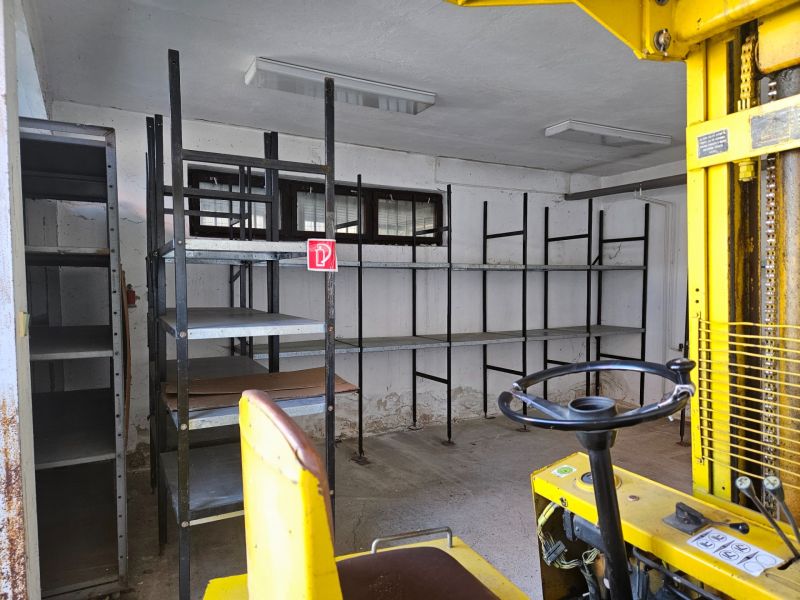 There are shelves and a yellow forklift in the garage, ready for storage.