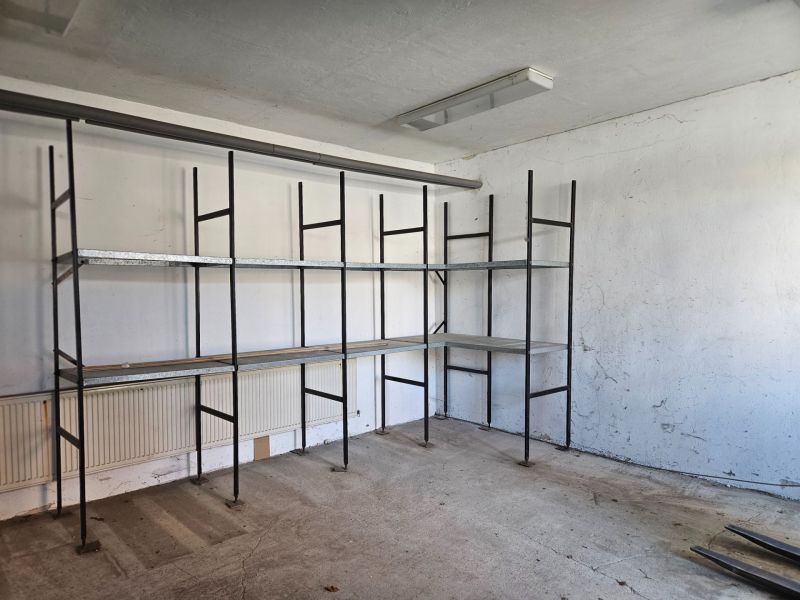 Shelves in a garage with a concrete floor and white walls.