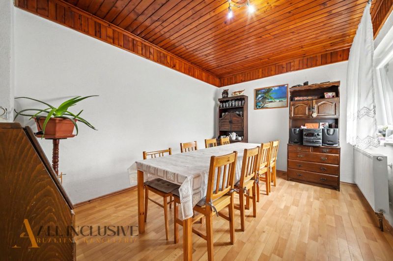 Dining room in a family house with a solid table, wooden decor flooring, and furniture.