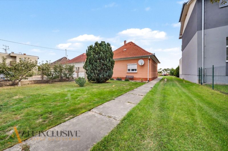 A family house in Povoda surrounded by lawn and trees, a concrete path leads to the house.