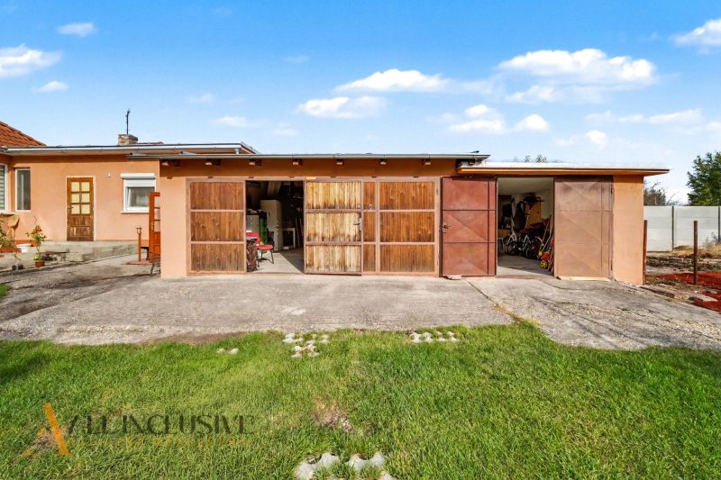 A family house in Povoda with a garage, wooden gates, and a yard with a lawn.