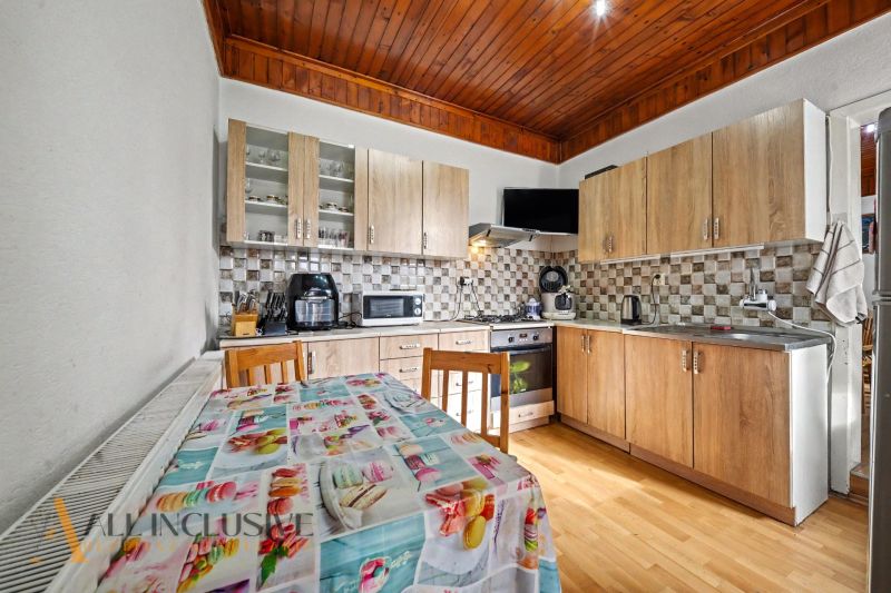 A kitchen in a family house with a wooden countertop, a floor with a wooden decor, and a dining table.