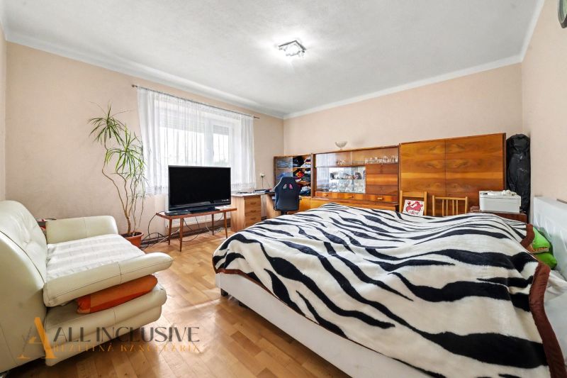 Bedroom with a bed, chair, television, and wooden floor decor in a family house.