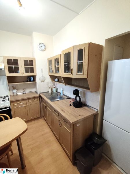 A kitchen in a studio apartment with a wooden decor floor and spacious cabinets.