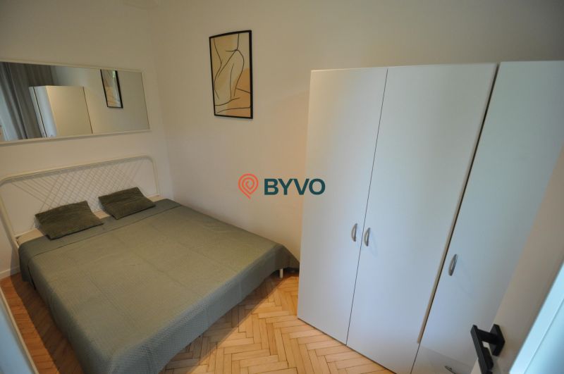 Bedroom in a 2-room apartment with a double bed and a wardrobe, floor with wooden decor.