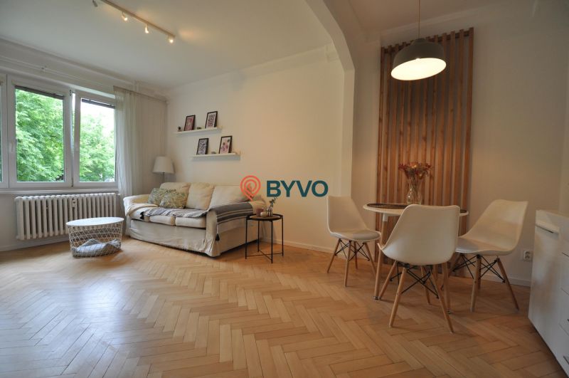 Living room with wood-patterned flooring, a sofa, and a dining table in a two-room apartment.