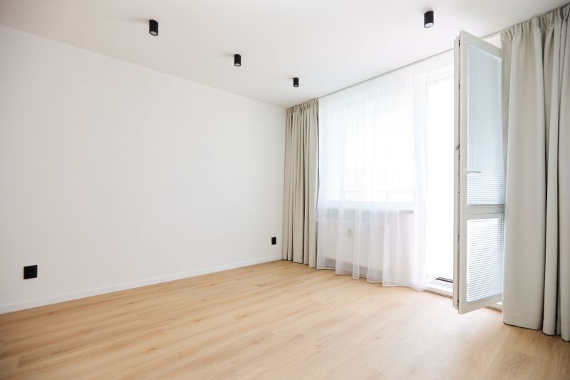 Interior of a 2-room apartment with a wooden decor floor, curtains, and open balcony doors.