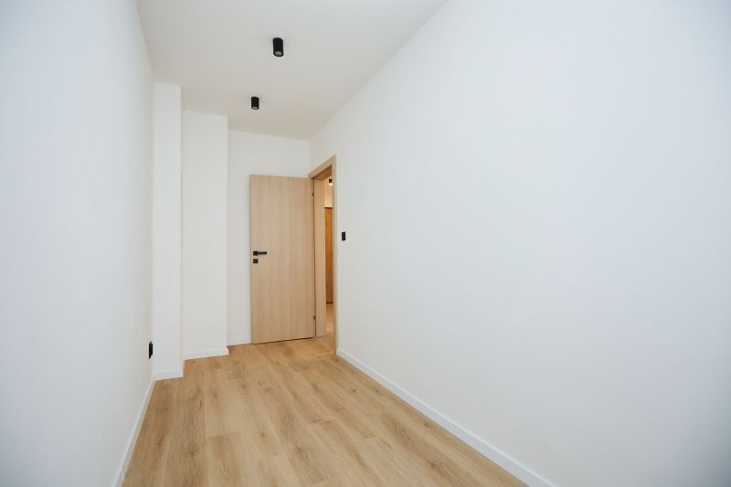 A hallway with a wooden decor floor and light-colored walls in a 2-room apartment.