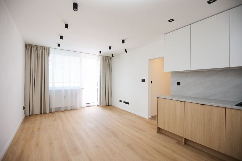A room in a 2-room apartment with a floor featuring a wooden decor and a kitchen unit.