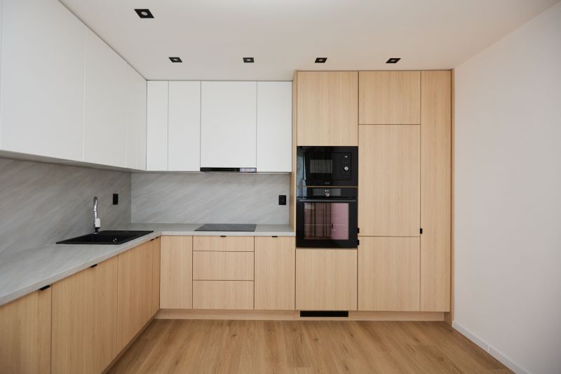 A kitchen in a 2-room apartment with white cabinets and a wood-patterned floor.