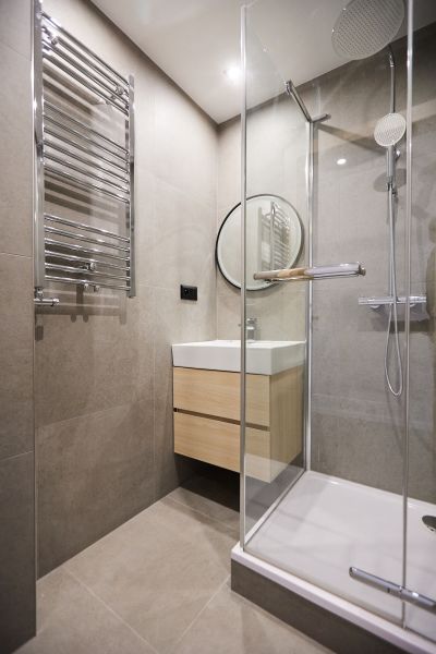 Bathroom in a 2-room apartment with a bathtub, shower, and mirror.