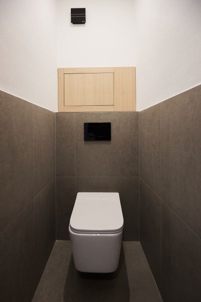 A toilet with neutral-toned tiles in a 2-room apartment.