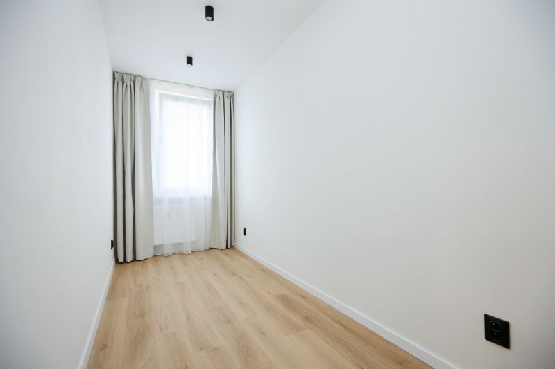 A room in a 2-room apartment with a wooden decor floor and a curtain.