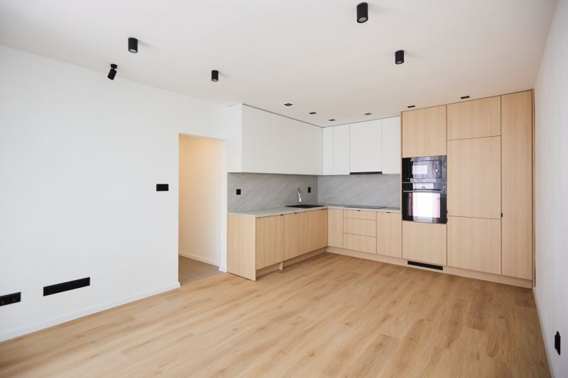 A kitchen in a 2-room apartment with a wooden decor floor and built-in appliances.