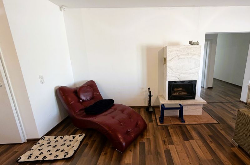A family house with a fireplace, a leather armchair, and a floor with a wooden decor.