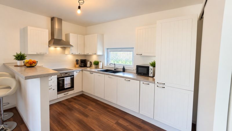 A kitchen in a family house with a wooden decor floor and white cabinets.