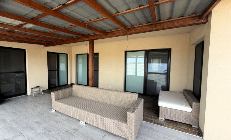 The outdoor space of a family house in Nickelsdorf with wicker furniture and a canopy.
