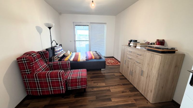 A room in a family house with a comfortable armchair and a bed, and a floor with a wooden decor.