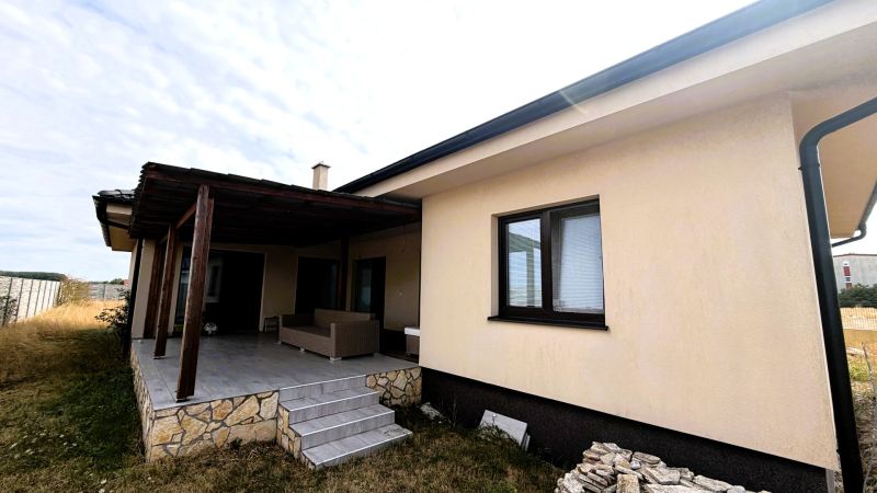 A family house in Nickelsdorf with a light facade and a covered terrace.
