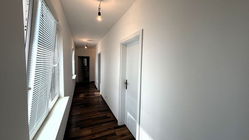 A device in a family house with a wooden decor floor and blinds on the windows.
