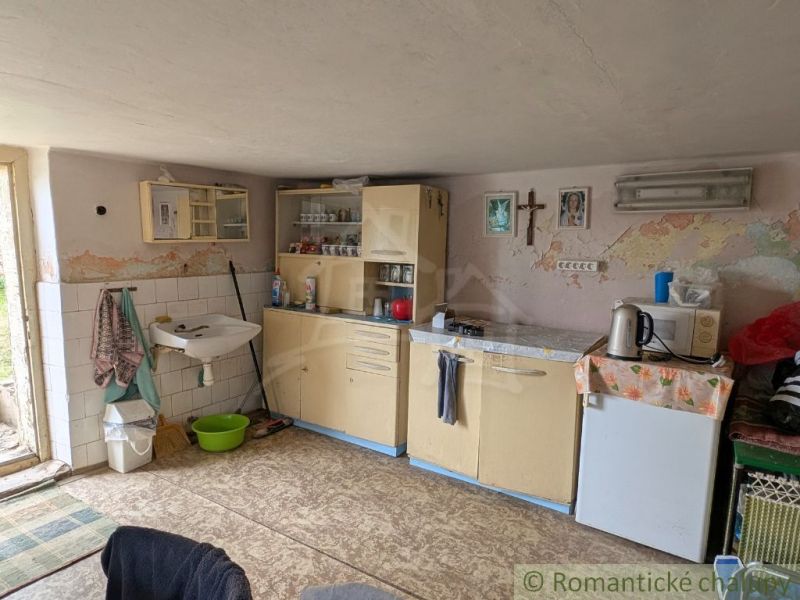 Kitchen unit with a sink, older furniture, and tiles in a family house.