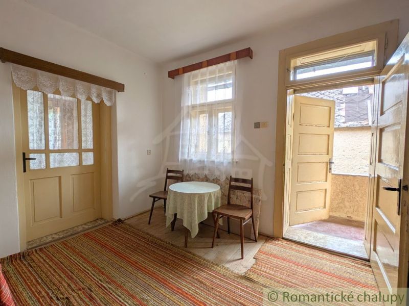 A room in a family house with carpets, a table, and chairs, a space full of light.