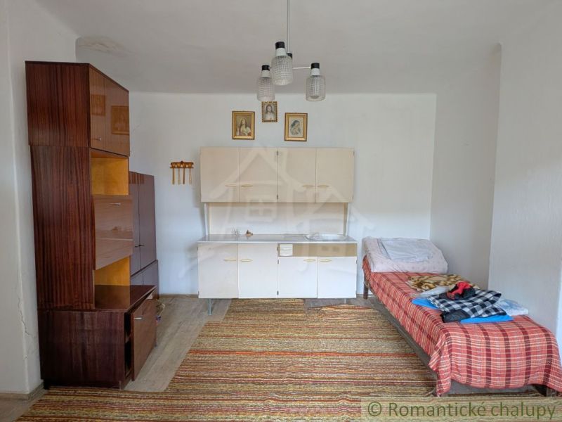 A room with simple furniture, a wooden decor floor, and a bed in a family house.