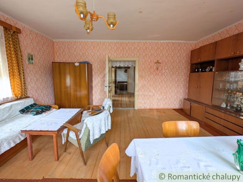 A room in a family house with a wooden decor floor, classic furniture, and patterned wallpaper.